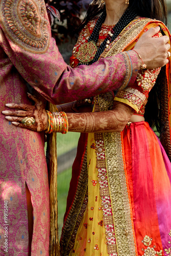 Tall Groom Holds Delicate Shoulders Of Beautiful Indian Bride