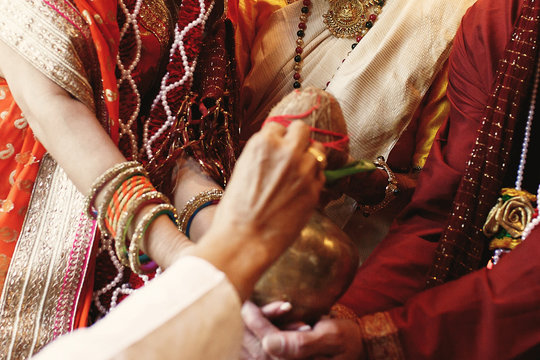 Indian bride puts a bronze bowl with coconut over her parents hands