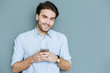 © zinkevych - Modern igen. Happy nice handsome man holding his smartphone and smiling to you while typing a message