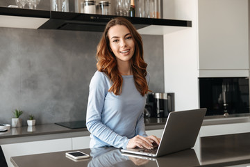 Wall Mural - Portrait of a happy young woman using laptop computer