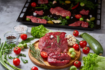 Wall Mural - Still life of raw beef meat with vegetables on wooden plate over vintage background, top view, selective focus