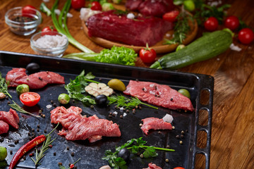 Wall Mural - Still life of raw beef meat with vegetables on wooden plate over vintage background, top view, selective focus