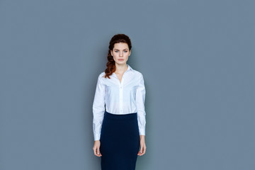 Professional success. Smart nice confident businesswoman standing against grey background and looking at you while working