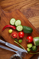 Wall Mural - fresh vegetables on the cutting board and knife over wooden background, selective focus, shallow depth of field