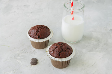 Two chocolate zucchini muffins and glass of milk on a white stone background. Copy space.