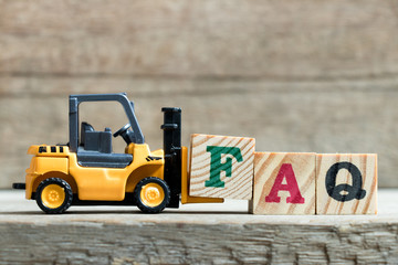 Poster - Toy yellow forklift hold letter block F to complete word FAQ (Abbreviation of Frequently asked questions) on wood background