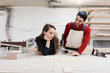© Rithor - young happy family standing at a work bench in a carpentry workshop, writing a project. Family business. startup business. young specialist designer.