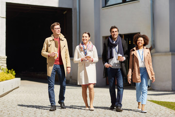 Canvas Print - business, education and corporate people concept - happy international group of office workers with conference badges drinking coffee and talking outdoors