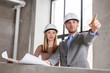 © Syda Productions - architecture, construction business and people concept - architects with blueprint and helmets at office pointing at something