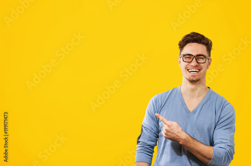 Fotomural hipster man in glasses pointing happily away on orange yellow background