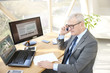 © sepy - Senior professional man consulting with his client. Portrait of a senior sales man sitting at office desk in front of laptop and talking in his mobile phone.