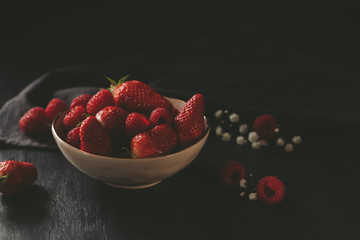 Dark moody food photography with fresh strawberries and raspberries