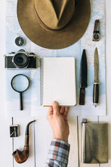 Wall Mural - adventure planning flat lay. travel vintage gear on map. traveler, explorer hand in frame holding em