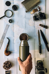 Wall Mural - adventure planning flat lay. travel vintage gear on map. traveler, explorer hands in frame pouring c