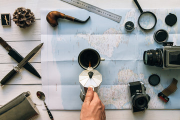 Wall Mural - adventure planning flat lay. travel vintage gear on map. man hand in frame pouring coffee from perco
