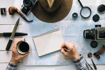 Wall Mural - adventure planning flat lay. travel vintage gear on map. man hands in frame writing on notepad. expl