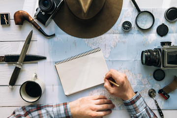 Wall Mural - adventure planning flat lay. travel vintage gear on map. man hands in frame writing on notepad. expl