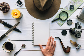 Wall Mural - adventure planning flat lay. travel vintage gear on white wooden table. man hand in frame holding no
