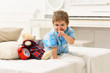 © Volodymyr - Time to sleep concept. Child in bedroom with silence gesture. Boy with happy face puts favourite toy on bed, time to sleep. Kid put plush bear near pillows and alarm clock, luxury interior background.