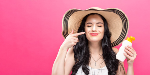 Wall Mural - Young woman holding a bottle of sunblock on a solid background