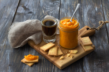 Wall Mural - Healthy raw orange jam with dried apricots in a glass jar with cookies and a cup of coffee on a wooden table. diet food. selective focus. free space. rustic style 