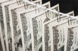 Parts of hundred dollar bills hanging on clerical clips on a rope on the dark background. Closeup, selective focus