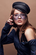 © monchak - Fashion portrait of beautiful young woman in black leather beret cap, denim blouse and light blue retro sunglasses