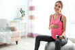 © New Africa - Young pregnant woman doing exercises with dumbbell at home