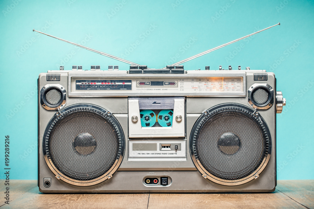 Retro outdated portable stereo boombox radio receiver with cassette recorder from circa late 70s front aquamarine wall background. Listening music concept. Vintage old style filtered photo - obrazy, fototapety, plakaty 