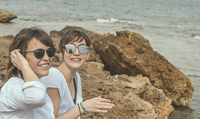 Two happy, smiling girls on the beach. Sensation of joy between two friends