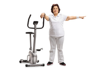 Poster - Elderly woman leaning on an exercise bike and pointing