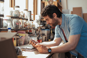 Wall Mural - Young craftsman using a tablet in his woodworking studio