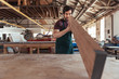 © mavoimages - Woodworker skillfully inspecting a wooden plank in his workshop