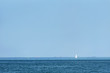A small sailing ship alone in the sea against a blue sky background