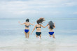 © oyoo - Three pretty beautiful asian women wearing colourful swimwear bikini with hat having fun and relax sunbathing on the beach in the summer