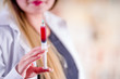© Fotos 593 - Close up of blurred smiling beautiful young woman wearing a lab coat and holding a syringe with blood in her hand