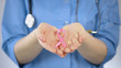 © motortion - Pink ribbon lying in palms of female doctor, breast cancer awareness campaign