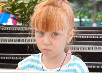 Portrait of a beautiful redheaded little girl. Child sad 