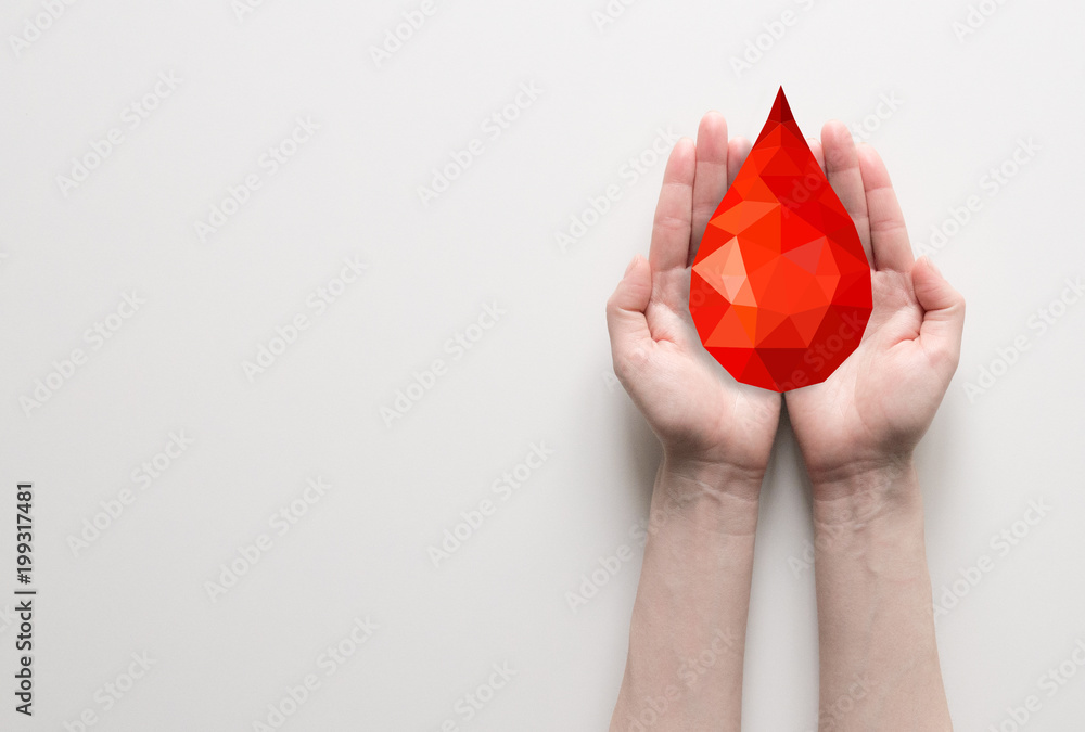 Two hands holding red polygonal blood drop, blood donation concept. Poster with place for text for clinic, hospital. - obrazy, fototapety, plakaty 