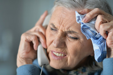 Wall Mural - Upset senior woman calling doctor