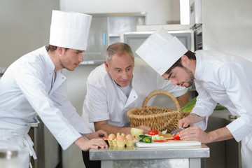 Wall Mural - chief chef watching his assistant garnishing a dish