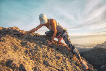 A young woman climbing a steep rocky mountain high above the sea level at Sandstone Peak, Malibu, California