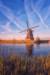 scenic sunset landscape with windmill, blue sky and reflection in the water. traditional dutch count