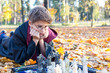 © Natali - cute boy in costume makes fun face, plays chess and reads book in autumn park, wizard, cosplay