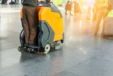 Fototapeta  - Man driving professional floor cleaning machine at airport or railway station.  Floor care and cleaning service agency
