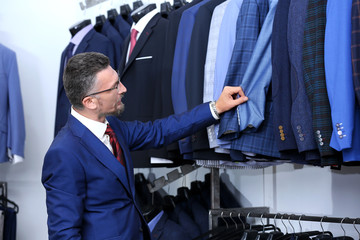 Canvas Print - Handsome man choosing suit in shop