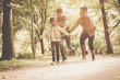 © Mladen - African American parents catching their daughter and running trough park.