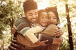 © Mladen - African American family hugging in park.