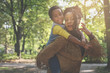 © Mladen - African American single mother carrying his daughter on piggyback in park.