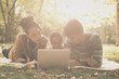 © Mladen - African American parents with their daughter in park using laptop.